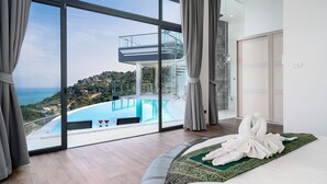 A modern hotel room with a large window overlooking a pool and a scenic view.