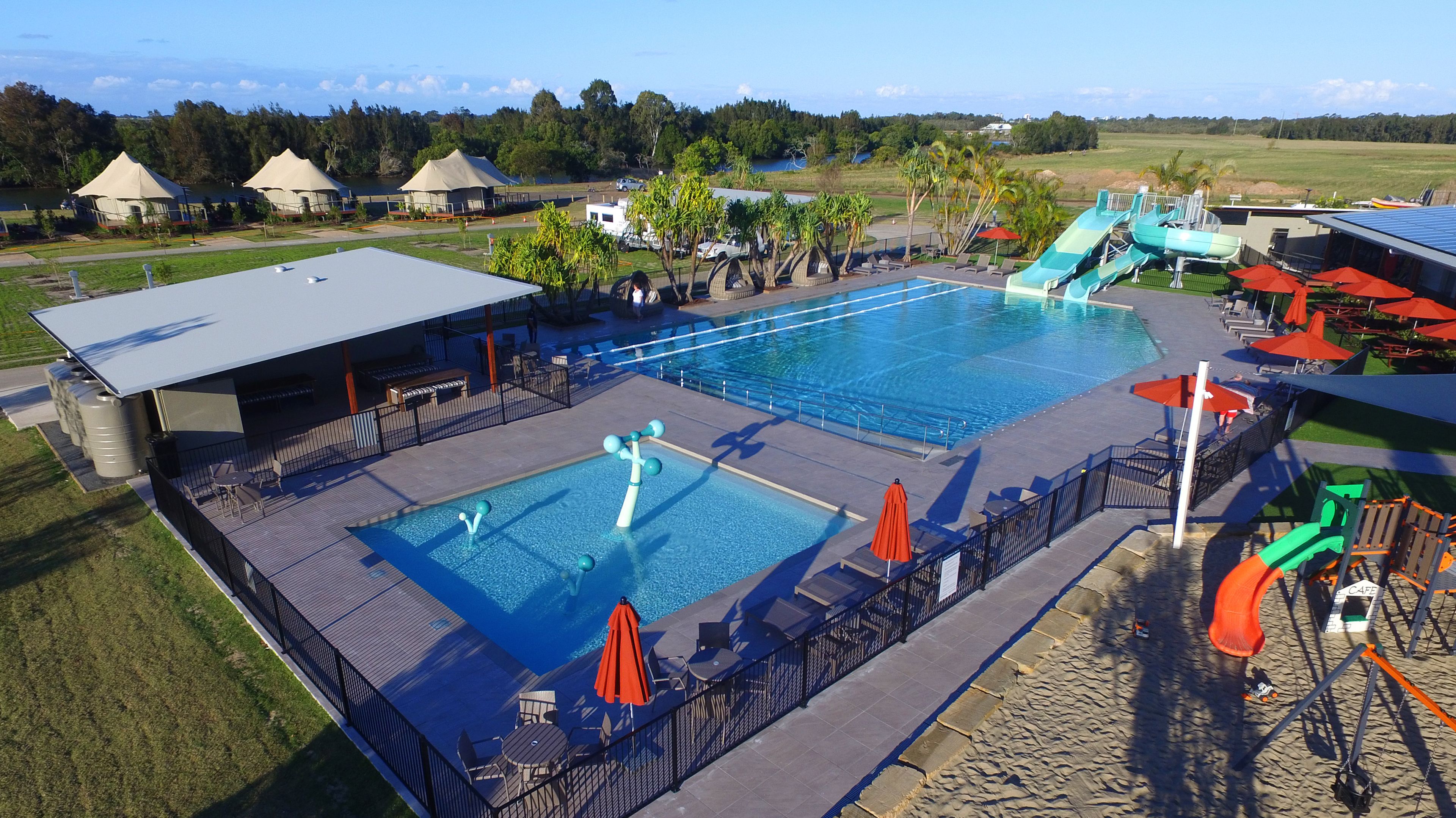 A large outdoor swimming pool with a slide, lounge chairs, and umbrellas.