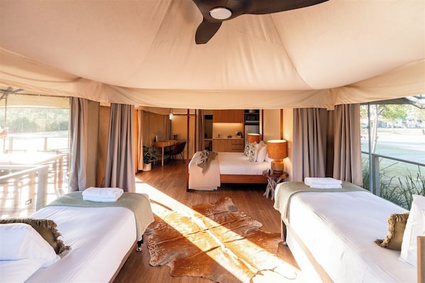 Quarto tipo tenda com duas camas, uma escrivaninha e vista para o exterior.