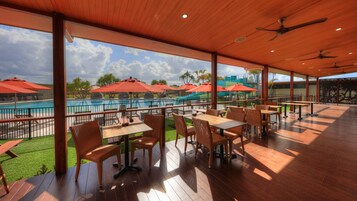 Une terrasse extérieure avec un plancher en bois, des meubles en osier et des parasols rouges.