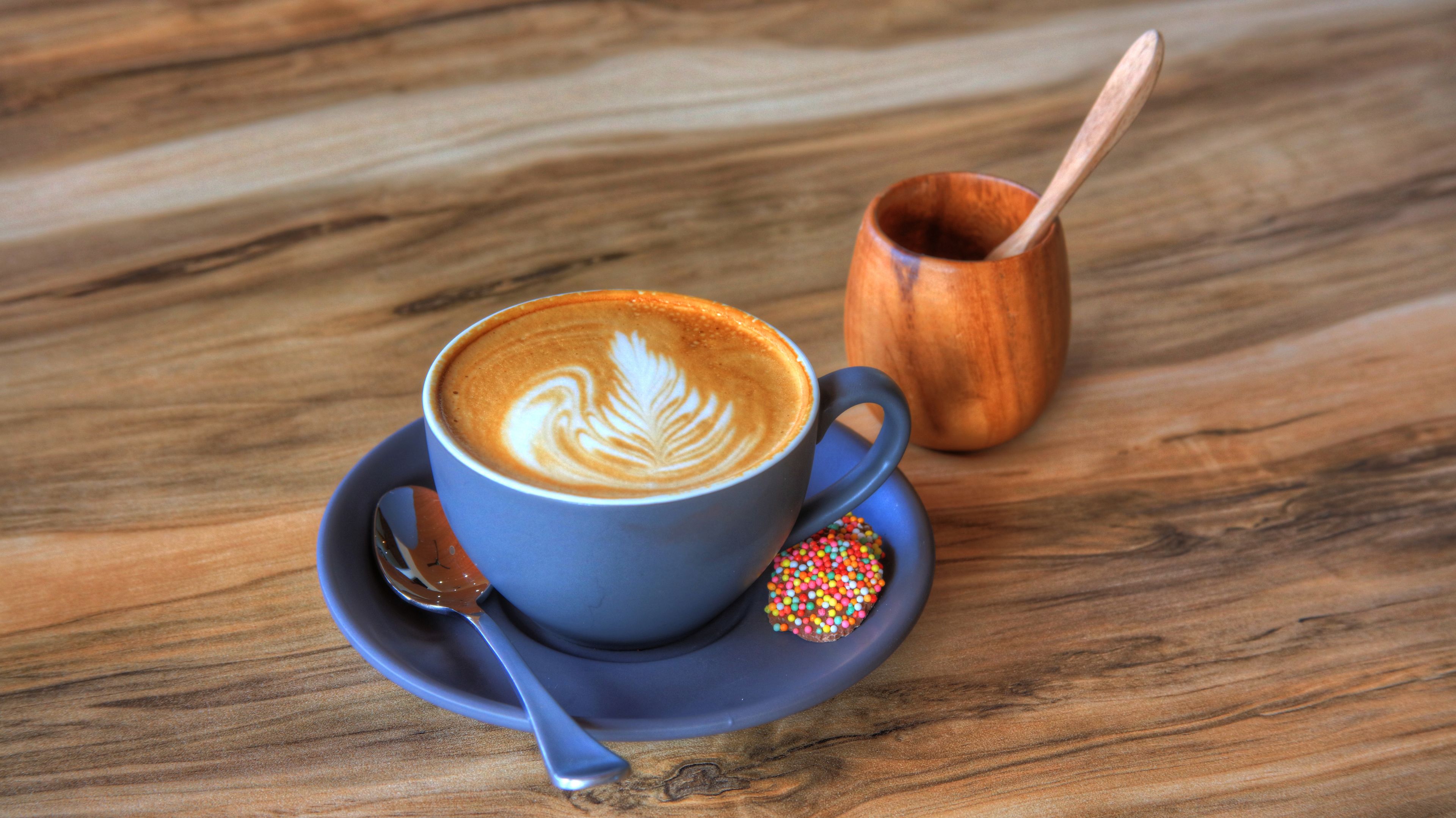 A cup of coffee with latte art on a wooden table.