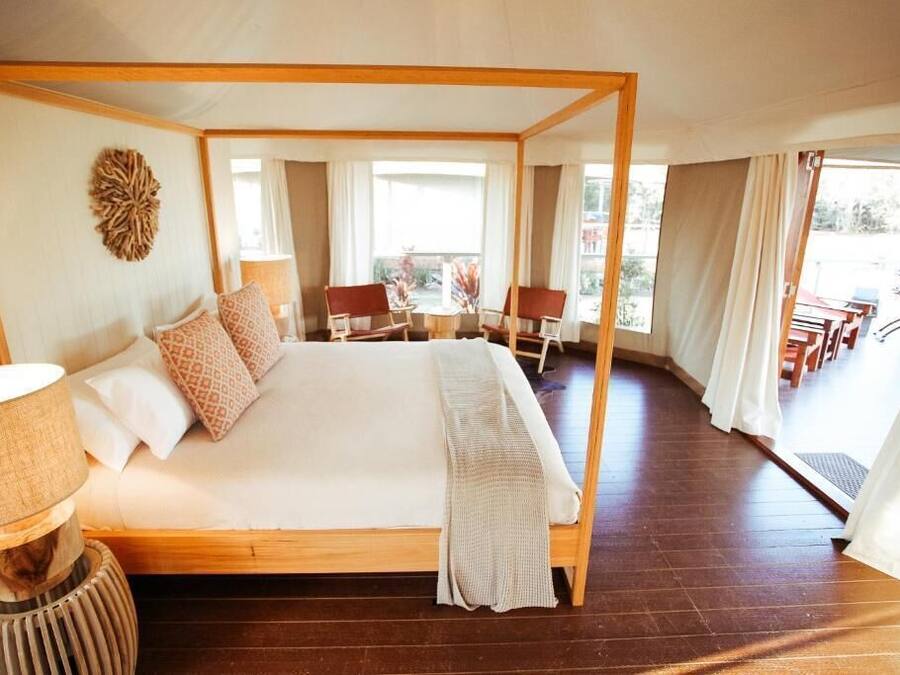 A four-poster bed with a wooden frame, a bedside lamp, and a decorative wall piece.