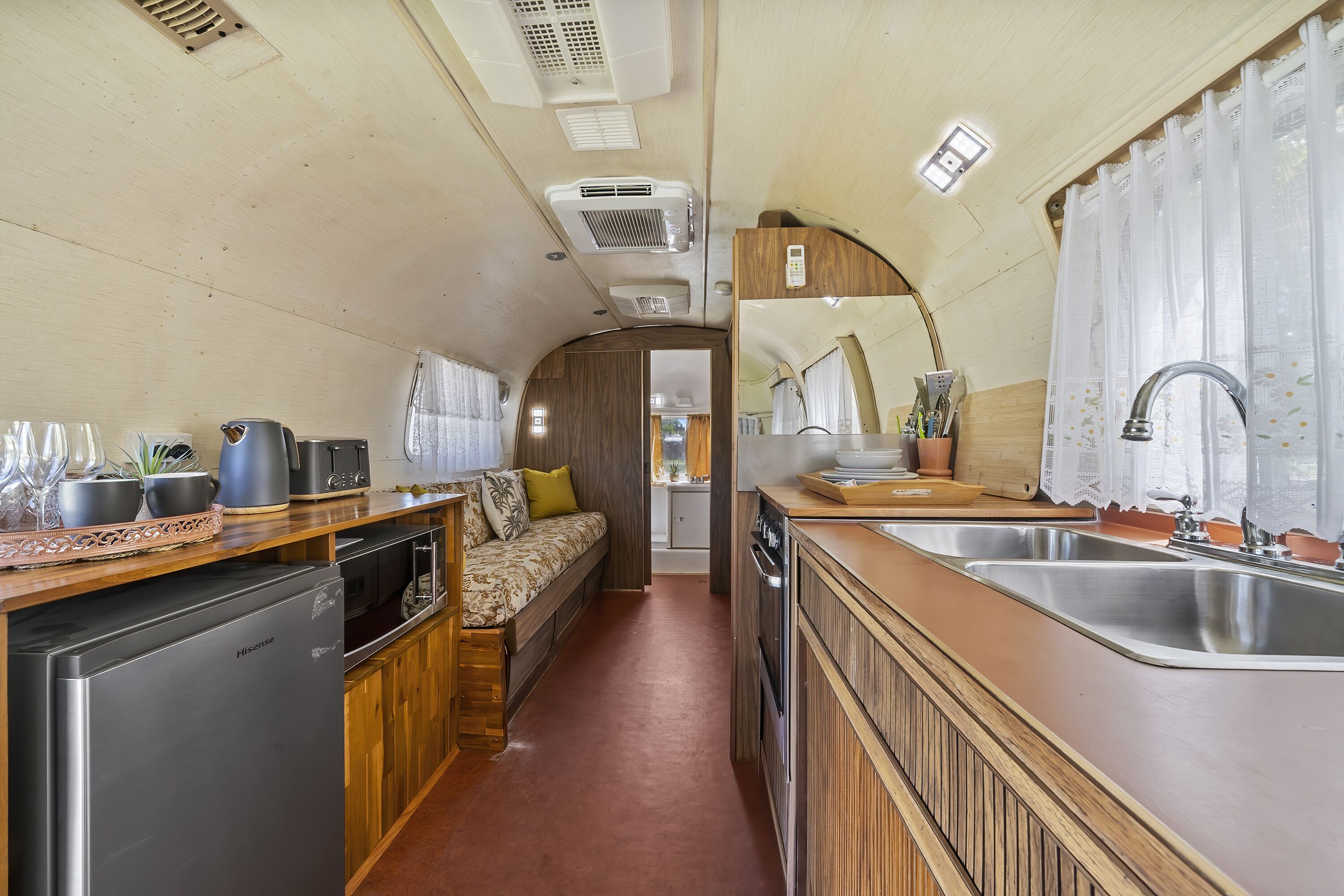 A compact RV kitchen with a refrigerator, stove, sink, and a small seating area.