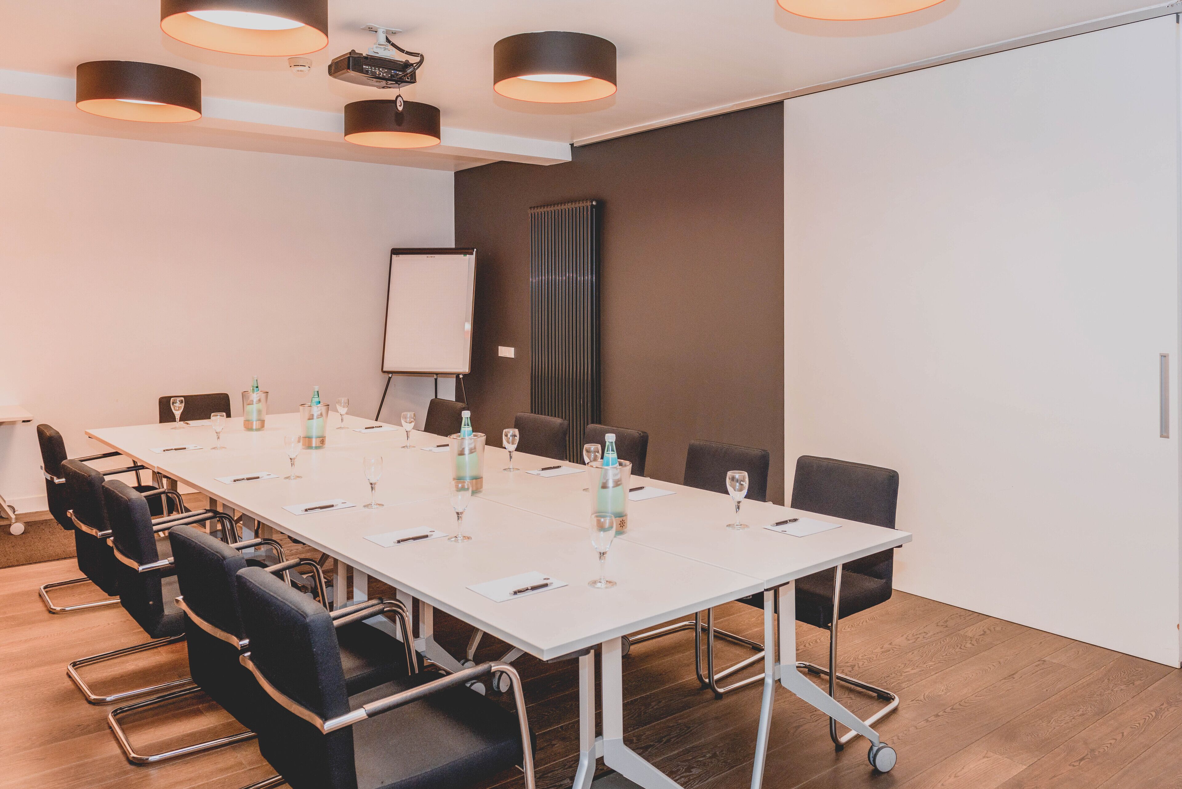 A conference room with a long table, chairs, and a whiteboard.