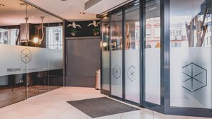 A modern reception area with a glass door, a welcome sign, and a geometric wall design.