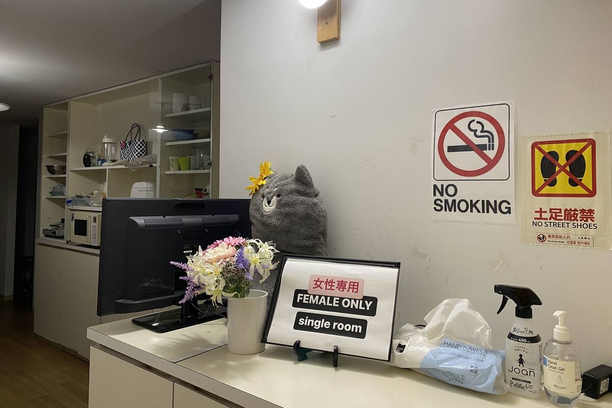 A reception area with a 'Female Only' sign, a 'No Smoking' sign, and a 'No Street Shoes' sign.