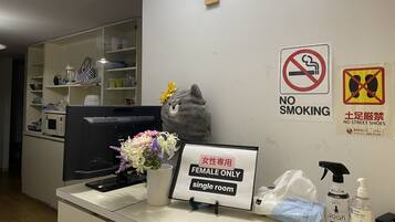 A reception area with a 'Female Only' sign, a 'No Smoking' sign, and a 'No Street Shoes' sign.