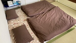 A room with two beds, each with brown bedding and a polka dot pillow. There is a small table with a flat-screen TV and a stack of folded towels. - Palette Takashimadaira - Hostel (Tokyo)