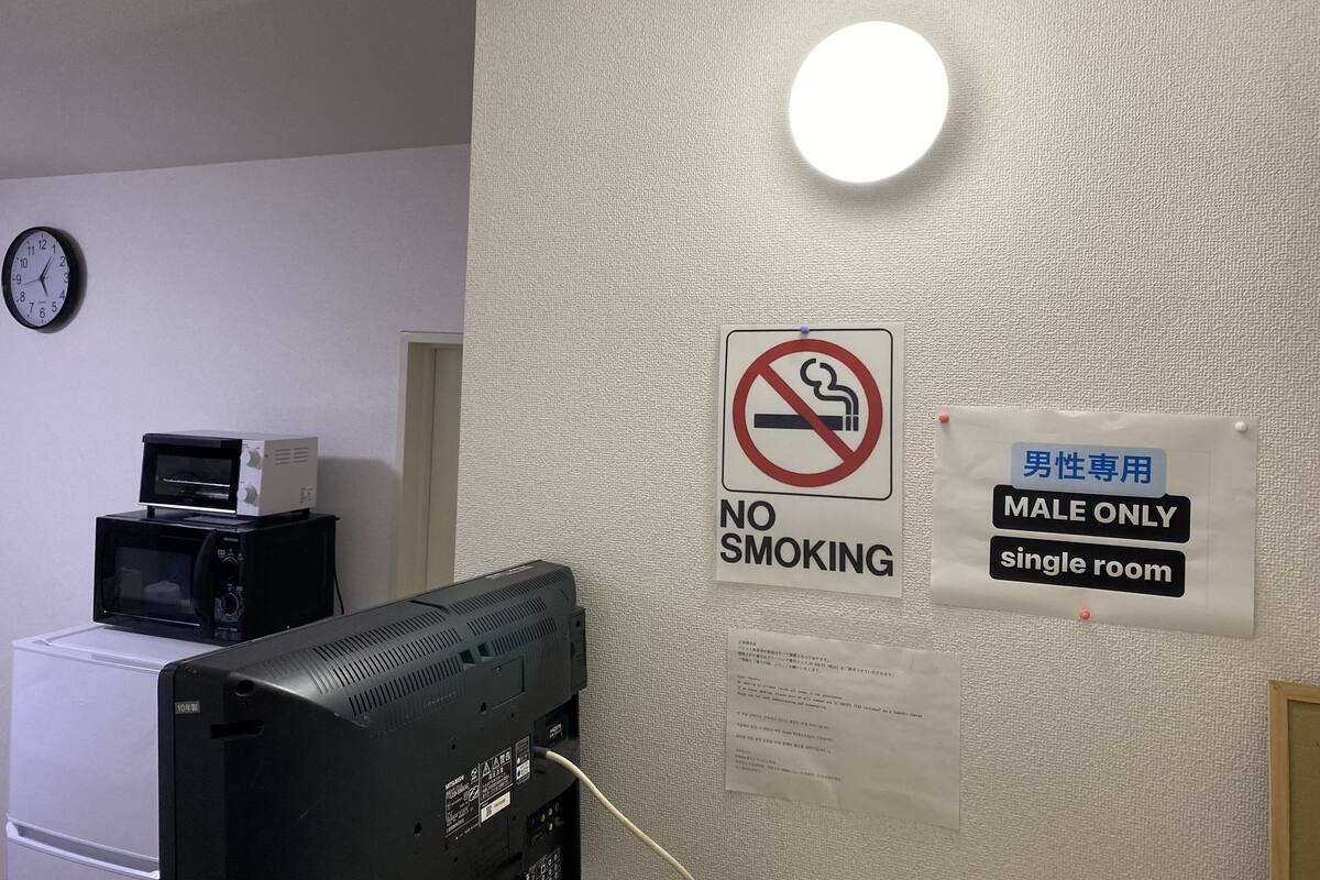 A hotel room with a no smoking sign, a male only sign, and a clock on the wall.