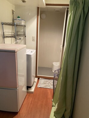 A compact bathroom with a washing machine, a toilet, and a shower area. - Palette Takashimadaira - Hostel (Tokyo)