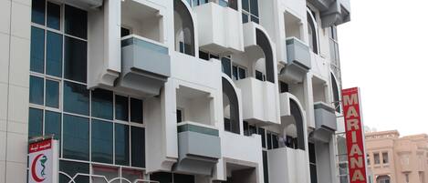A modern building with multiple balconies and large windows. There are signs for a pharmacy, Gulf Stream, and a hotel named Mariana.