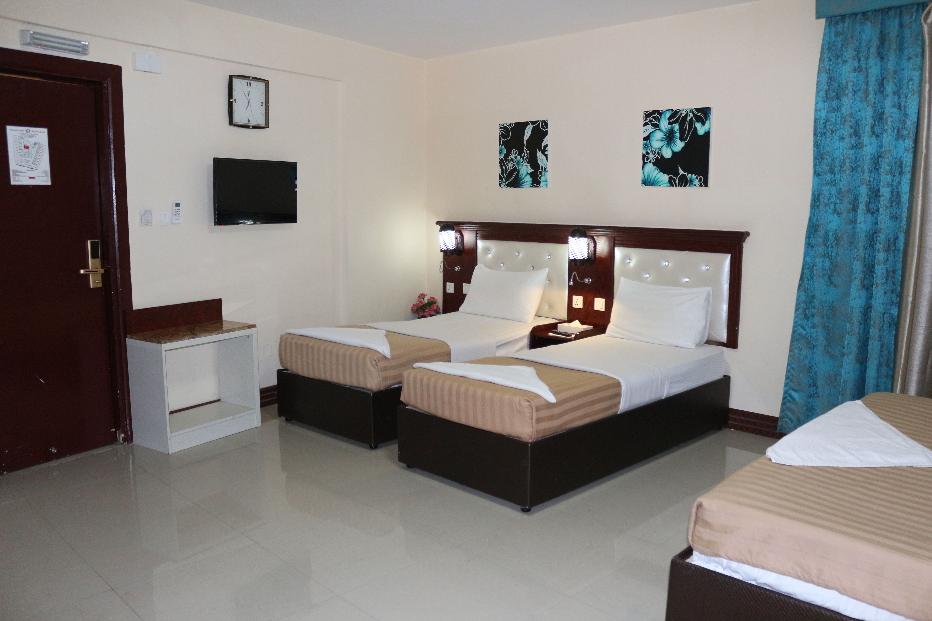 Habitación de hotel con dos camas, un televisor, un reloj y obras de arte en las paredes.
