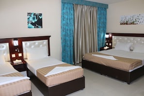A hotel room with two beds, a nightstand, a lamp, and a painting on the wall. - Mariana Hotel (Dubai)