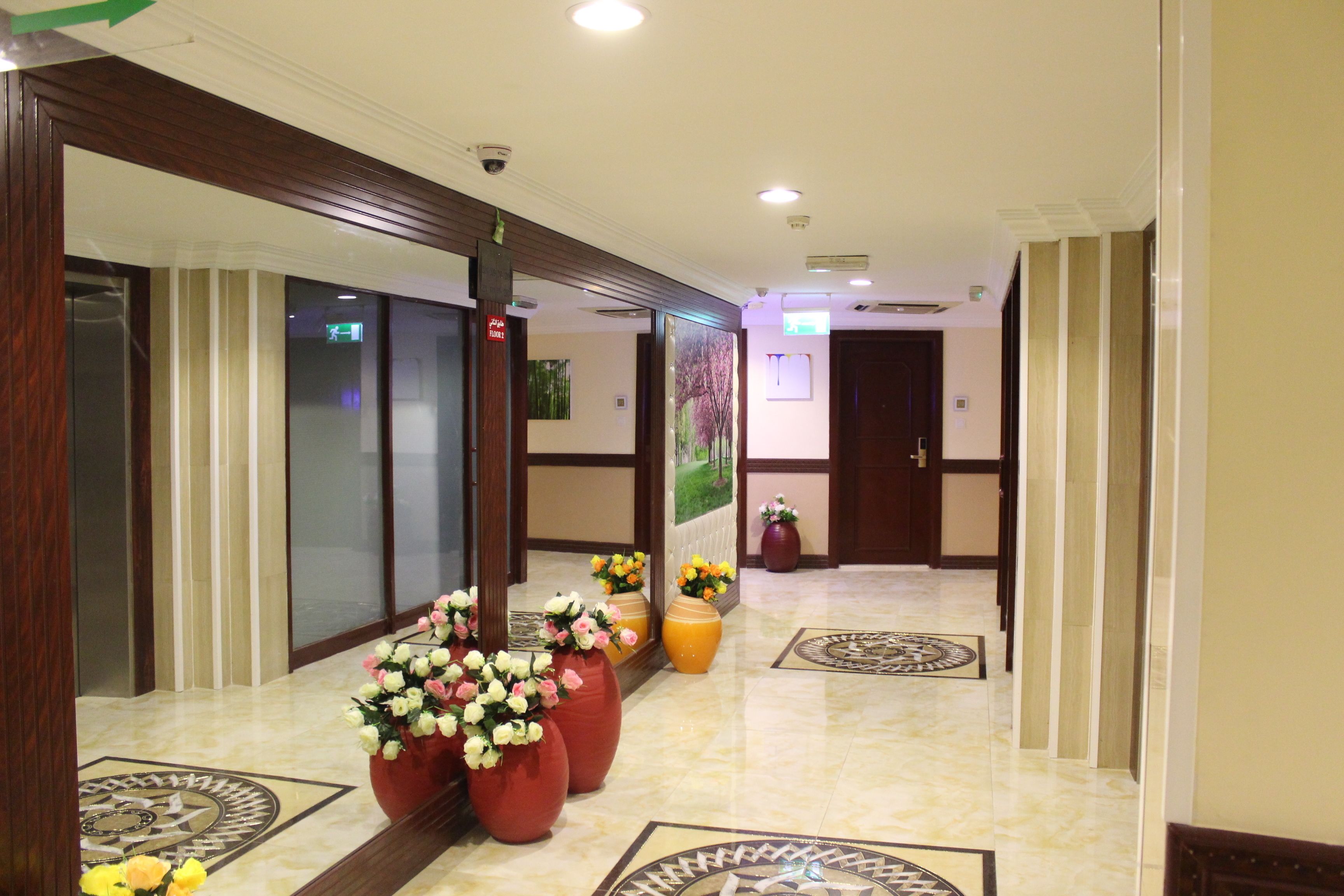 Un hall d’hôtel avec un sol en marbre, de grandes plantes en pot et un comptoir d’accueil.