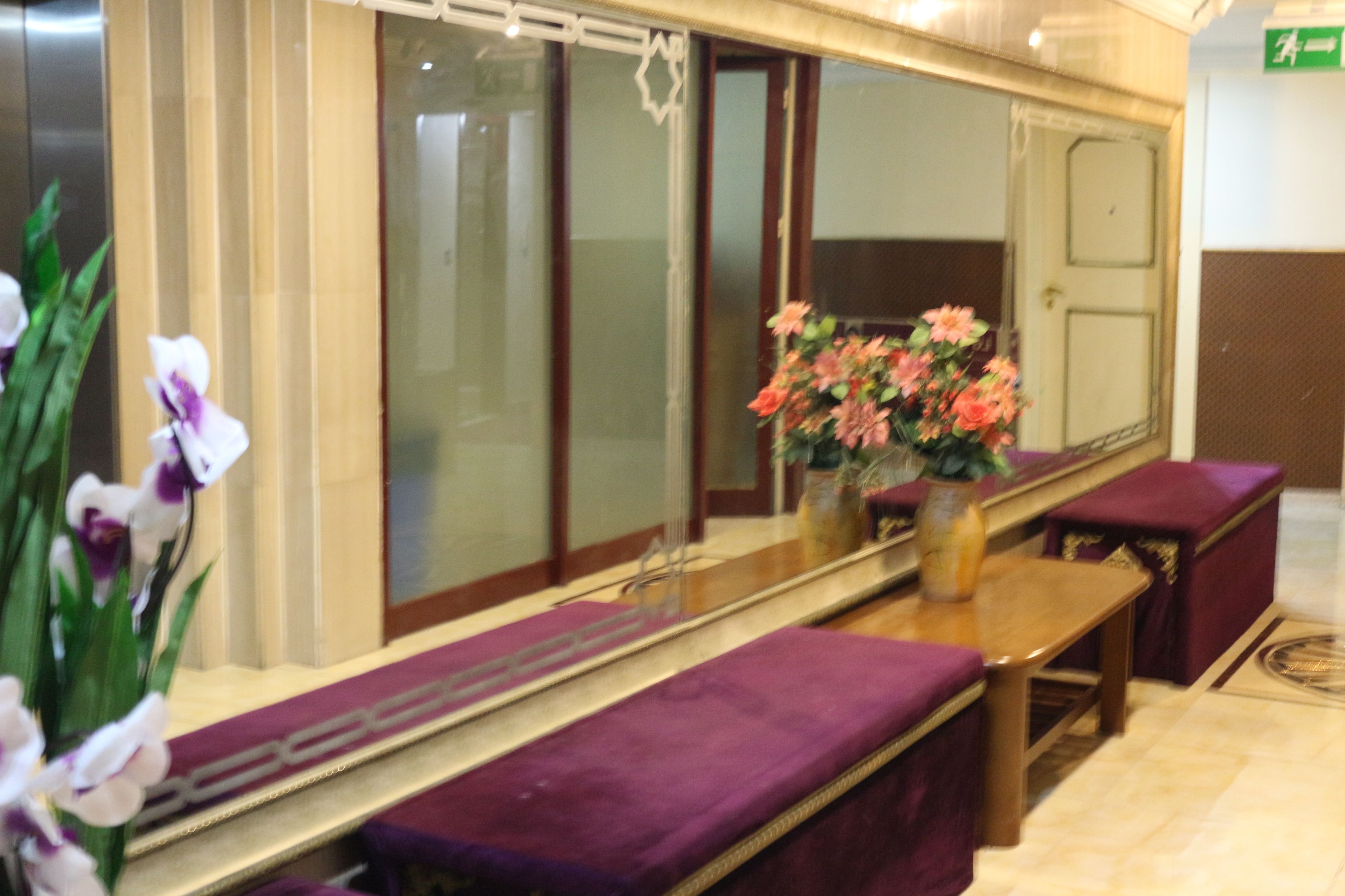 A reception area with a long counter, purple cushioned seating, and a vase with flowers.