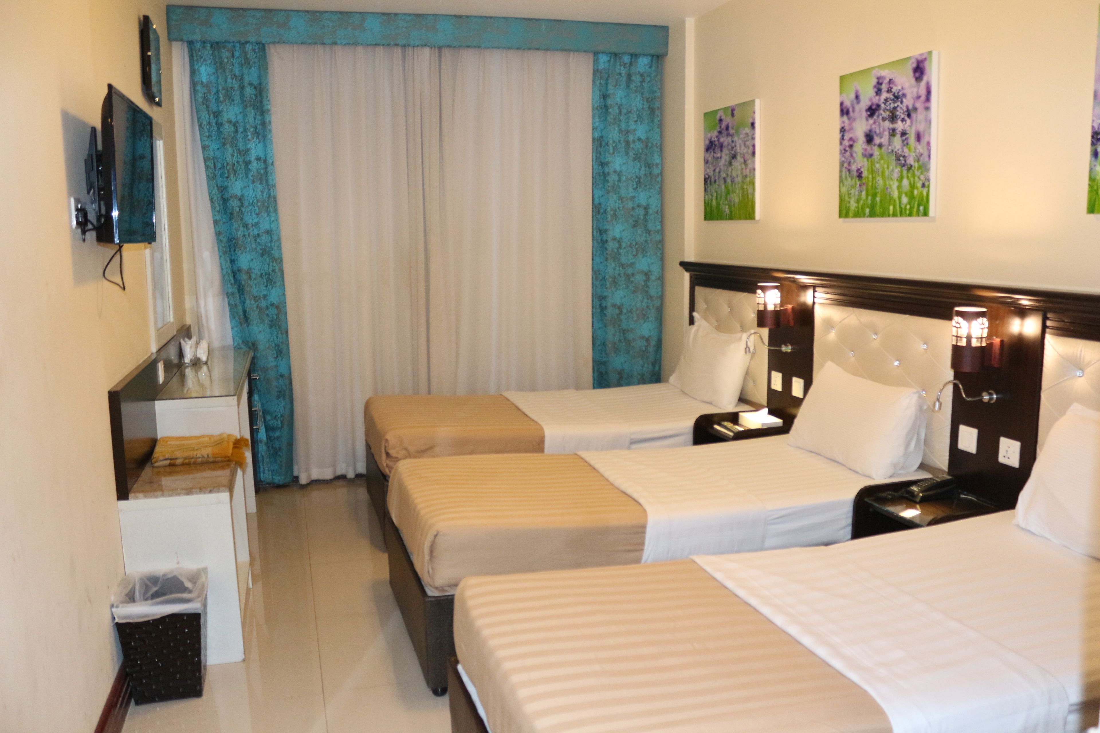 A hotel room with two beds, a desk, a chair, and a television.