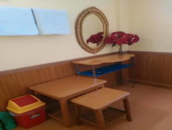 A corner of a room with a wooden bench, a small table, and a mirror on the wall. - Royal Flower Guest House (Pyin Oo Lwin)