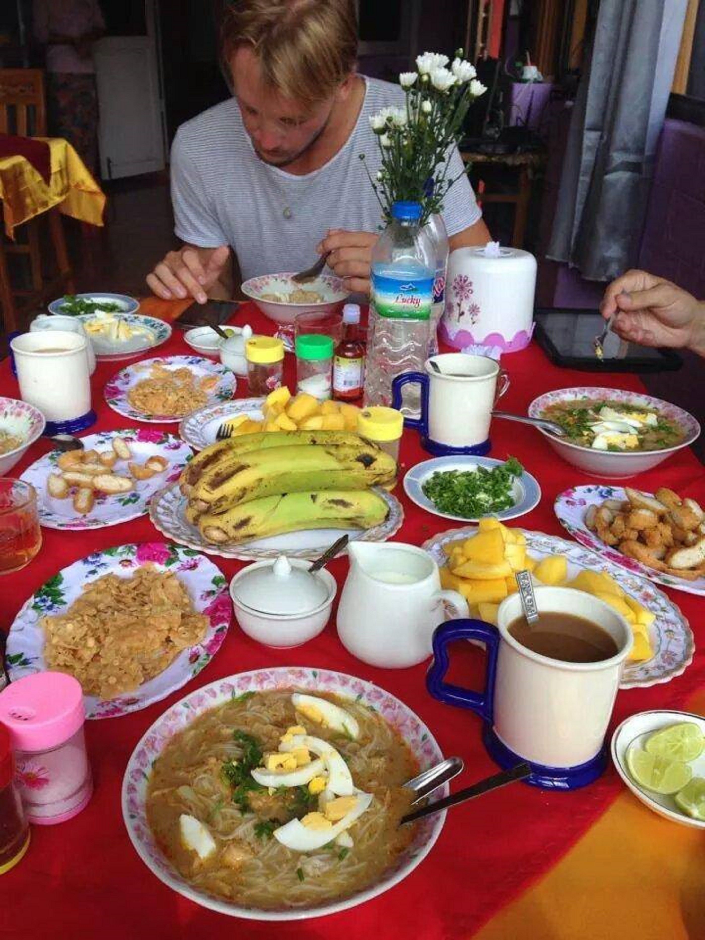 A dining table with various dishes, including a bowl of soup with eggs, a plate of fried food, and several bottles of beverages.