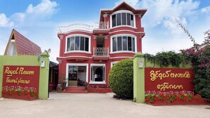 A large, red and white colonial-style building with a balcony and multiple windows. - Royal Flower Guest House (Pyin Oo Lwin)