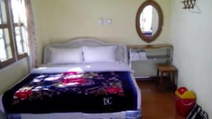 A bedroom with a bed, a bedside table, a mirror, and a window. - Royal Flower Guest House (Pyin Oo Lwin)