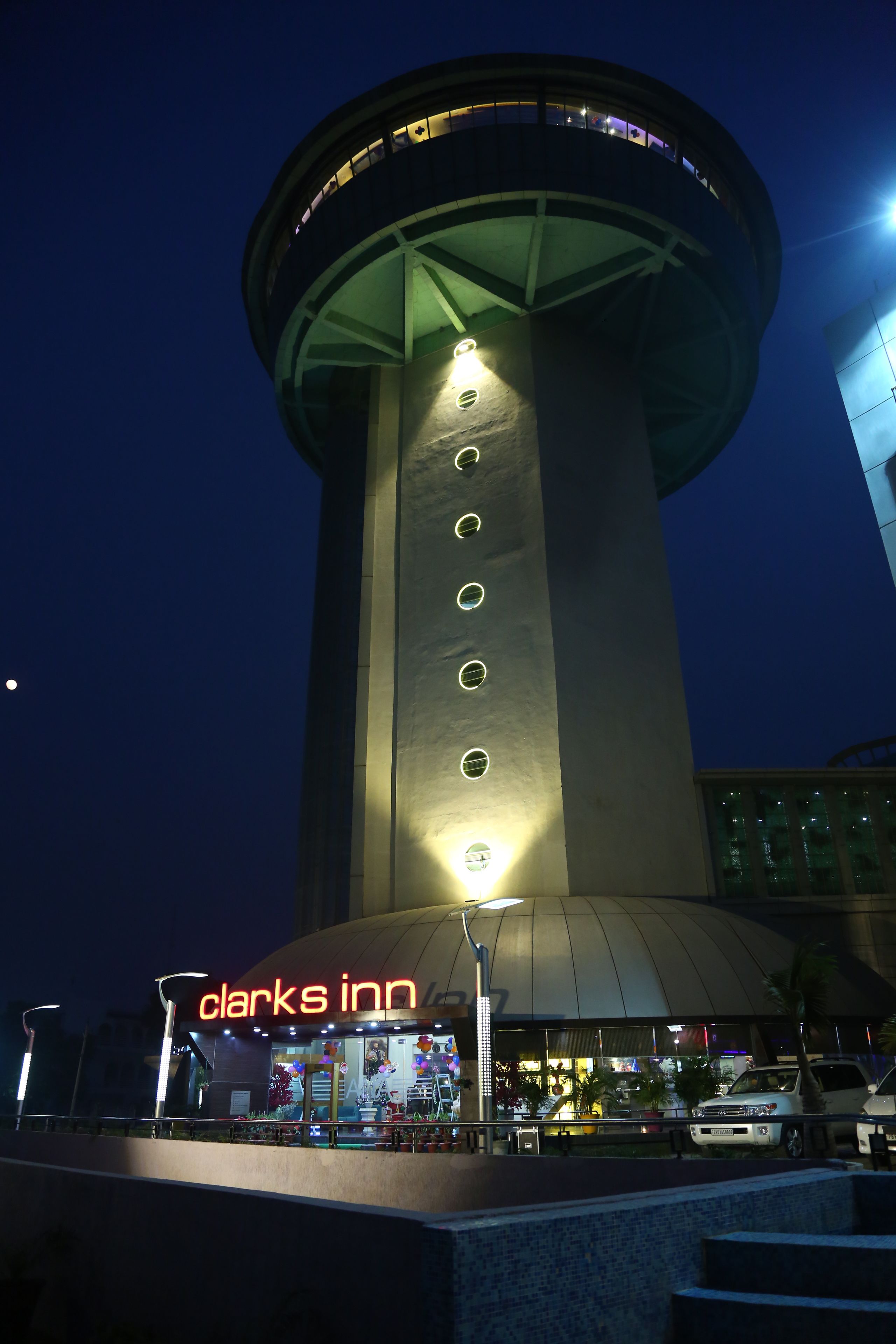 A hotel with a prominent tower structure, a neon sign, and a well-lit entrance.