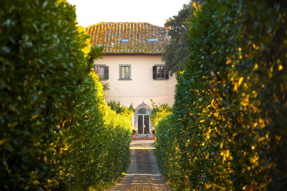 A pathway leading to a building with a tiled roof and a central entrance.