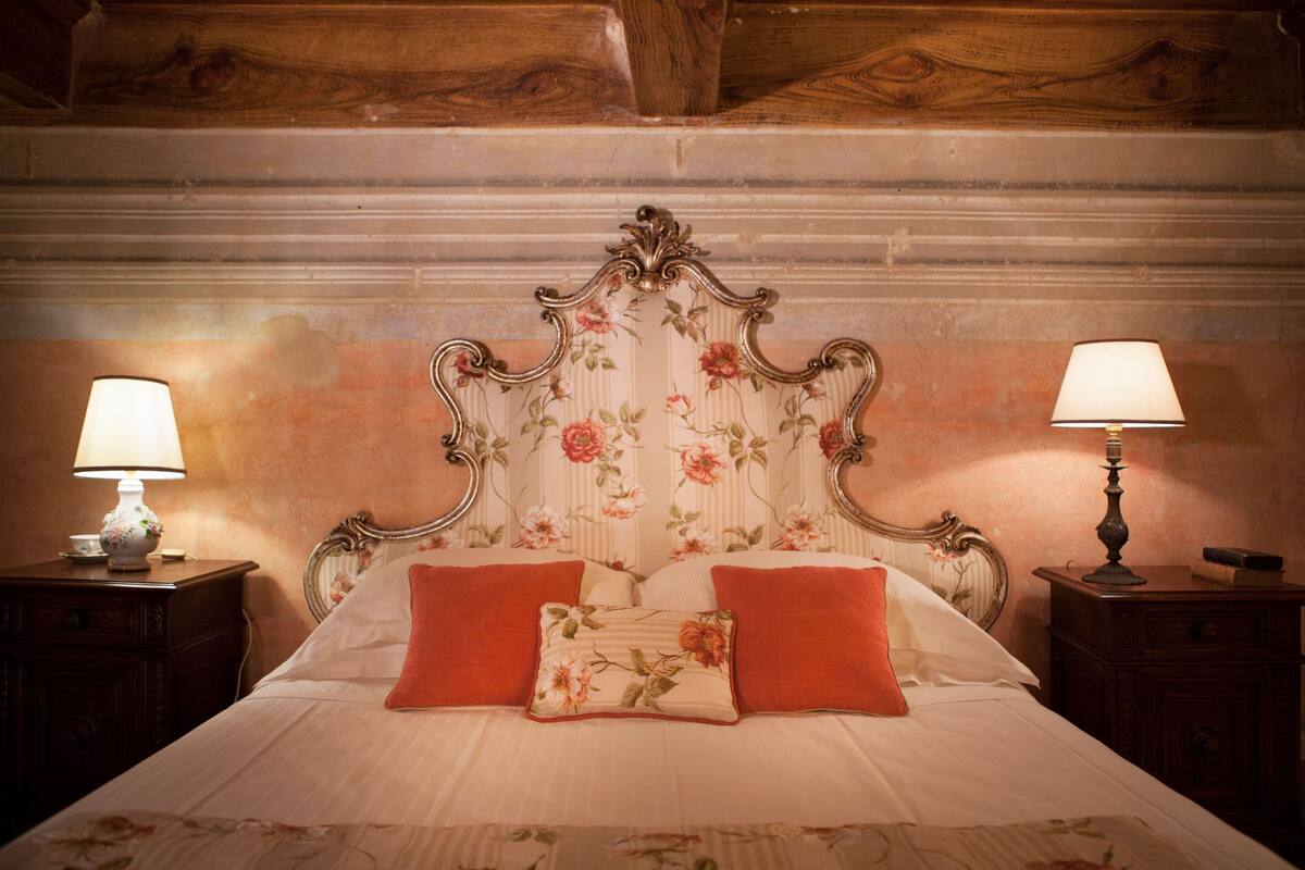 A bed with a floral headboard, two bedside tables with lamps, and a floral bedspread.