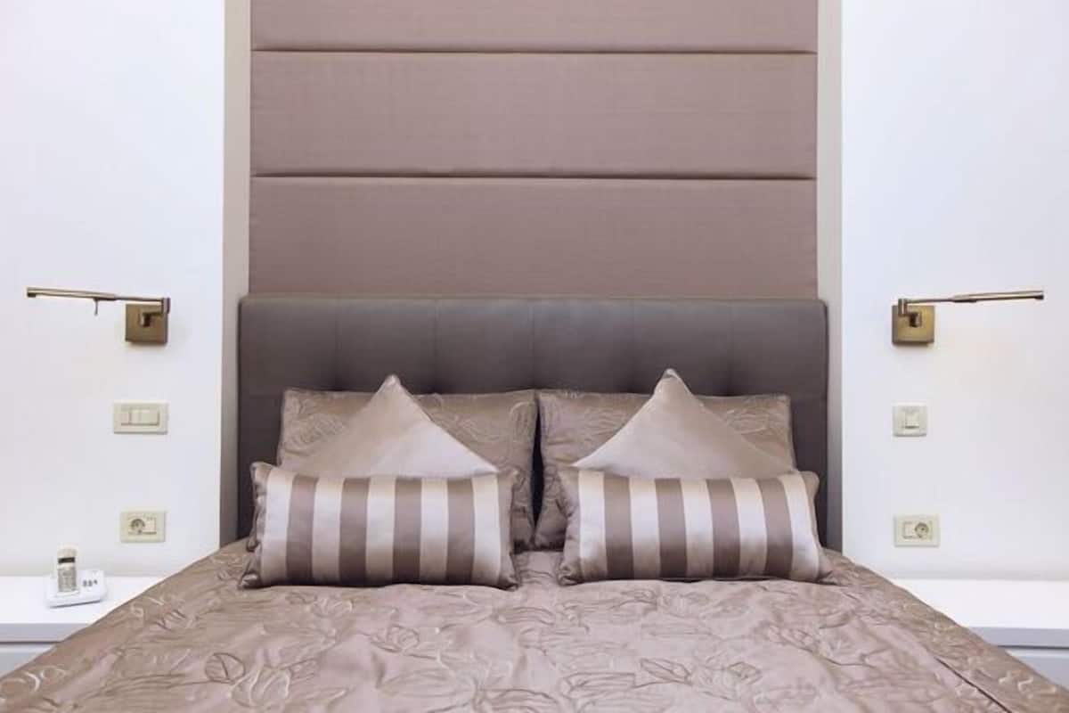 A bedroom with a large bed, two bedside tables, and a headboard with built-in lighting.