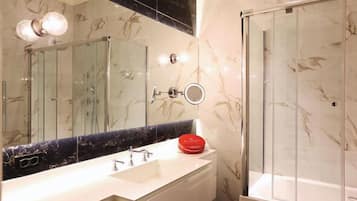 A bathroom with a large mirror, a white sink, and a glass-enclosed shower.