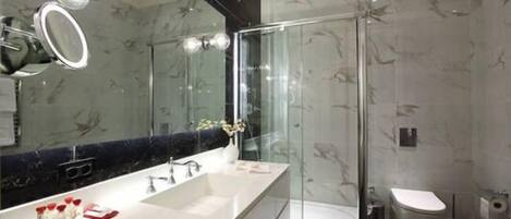 A modern bathroom with a large mirror, a glass shower enclosure, and a white sink.