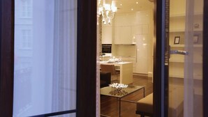 A modern kitchen with white cabinets, a dining area with a glass table, and a chandelier. - Pera Residence (Istanbul)
