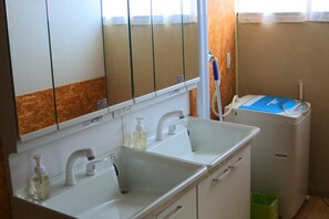 A bathroom with two sinks, a mirror, and a washing machine. - Retro Boy Coffee (Yuni)