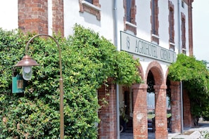 The exterior of the Agrihotel Crema with a signboard, brick arches, and a street lamp. - Agriturismo Ponte di Rialto (Crema)