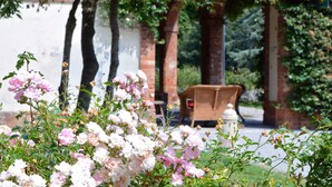 A garden with blooming flowers and a brick structure in the background. - Agriturismo Ponte di Rialto (Crema)