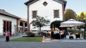 An outdoor seating area with tables and chairs, a building with a white facade and brown accents, and a fire hydrant on the ground. - Agriturismo Ponte di Rialto (Crema)