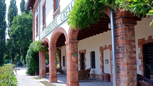 A brick building with arches and a sign reading "AGRICHOTEL CREM". - Agriturismo Ponte di Rialto (Crema)