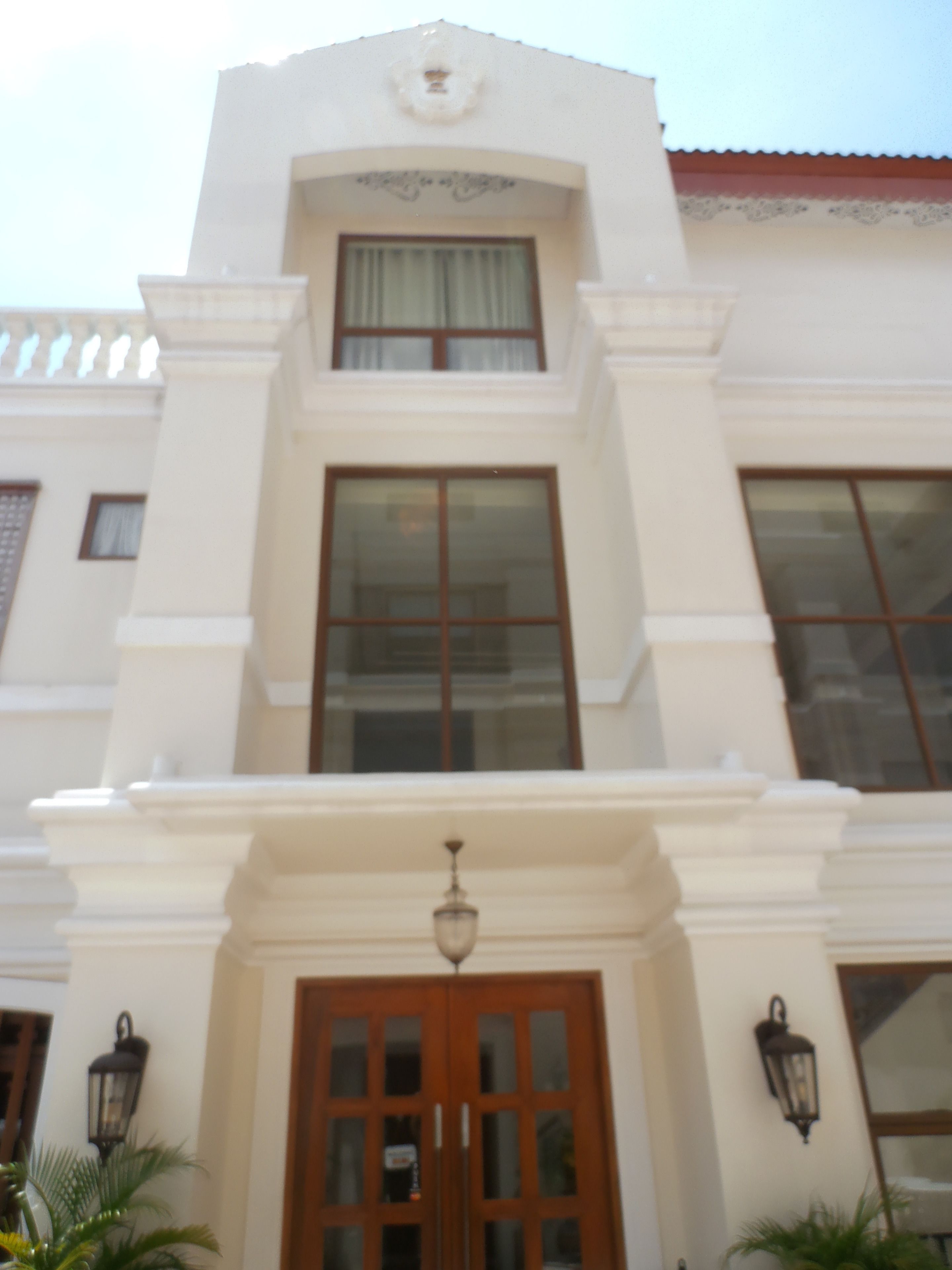 A building with a symmetrical facade, a central entrance with a wooden door, and two side lanterns.