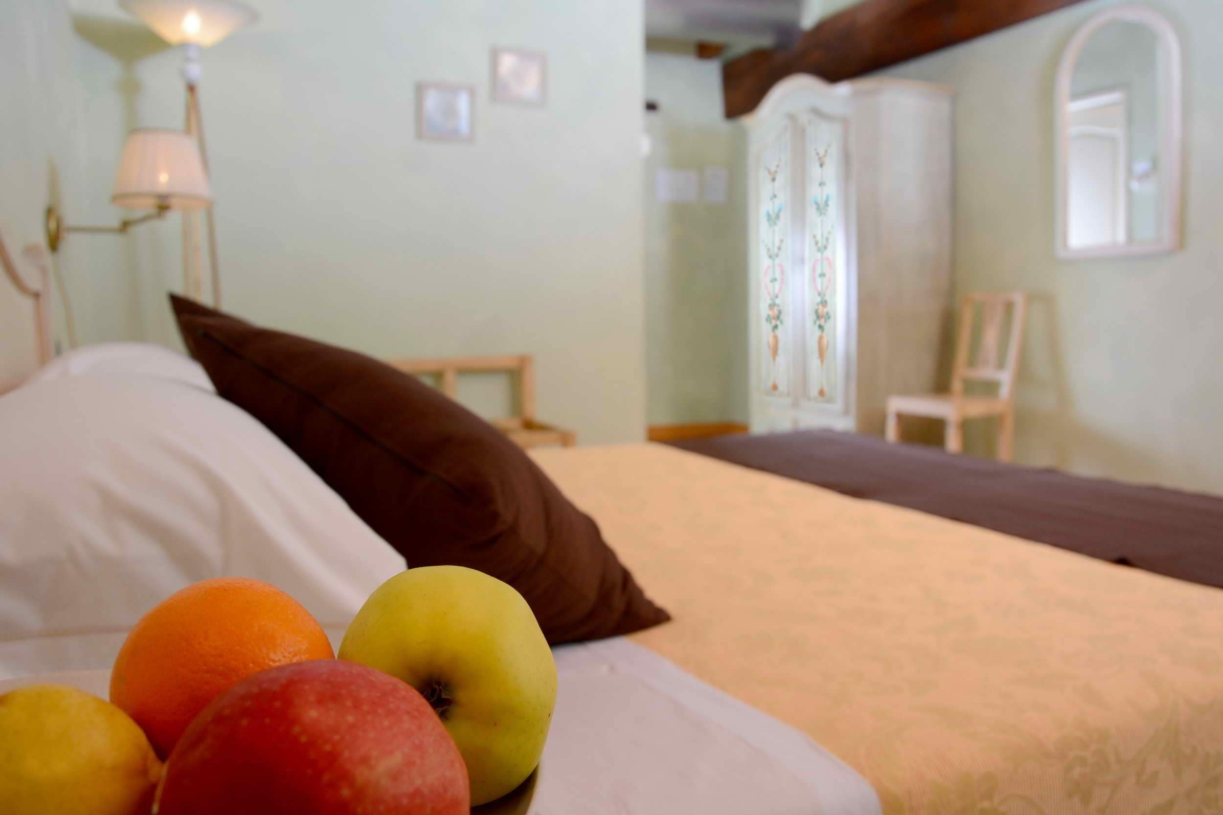 Un letto con cuscini e frutta sul copripiumino.