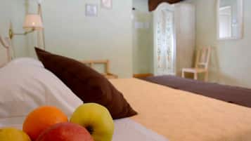 Una cama con almohadas y fruta sobre el cubrecolchón.
