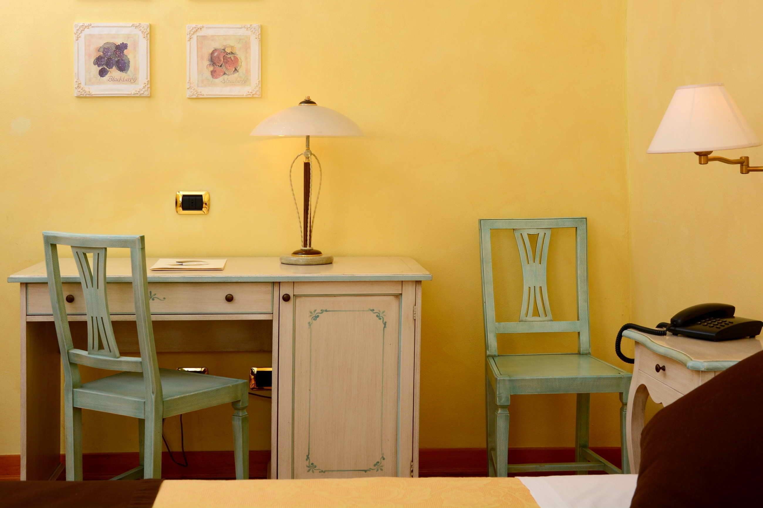 Une petite pièce comprenant un bureau, deux chaises, une lampe et un téléphone posé sur une table d’appoint.