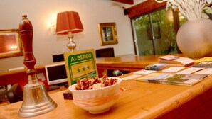A hotel reception area with a wooden counter, a bowl of snacks, a sign for 'Albergo', a lamp, and a vase with flowers. - Albergo Antica Hostelleria (Crema)