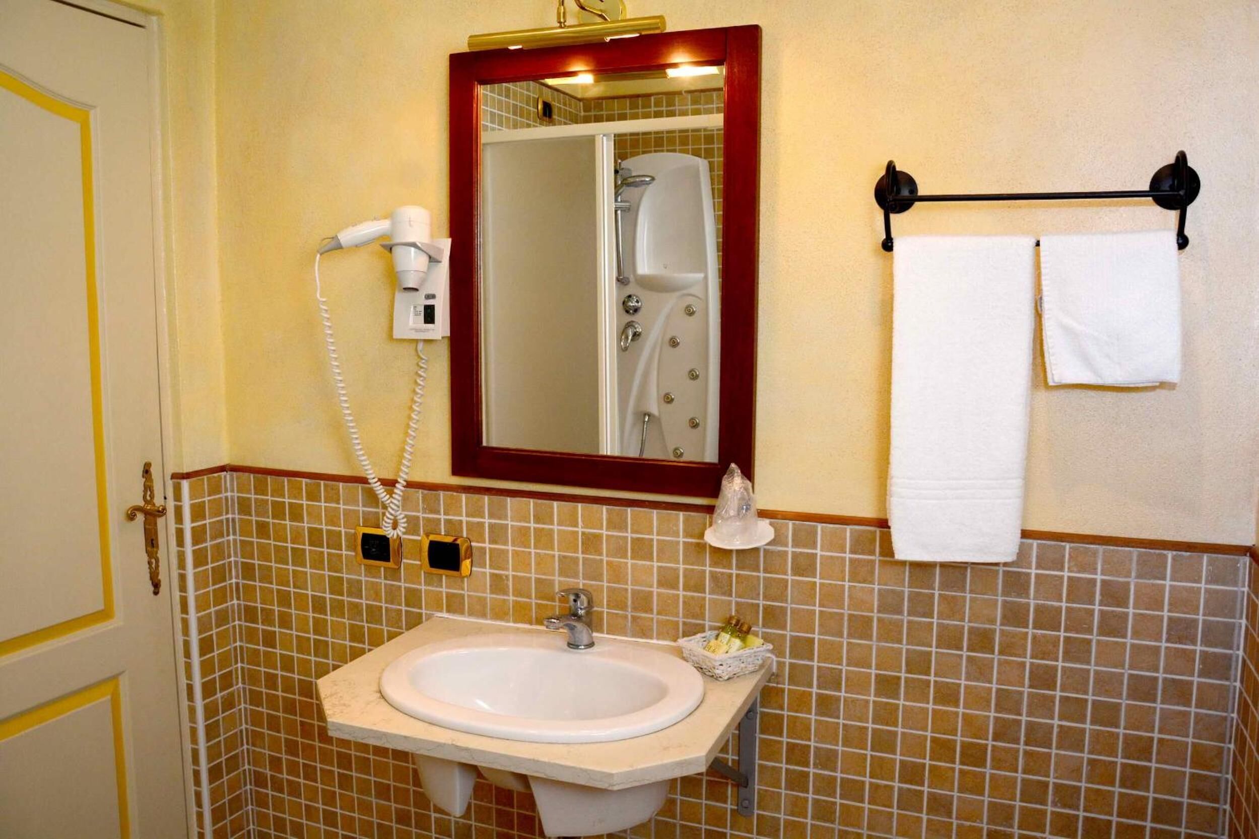 Une salle de bain équipée d’un lavabo, d’un miroir, d’un porte-serviettes et d’un sèche-cheveux.