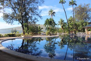A swimming pool with clear water reflecting trees and a mountain in the background.