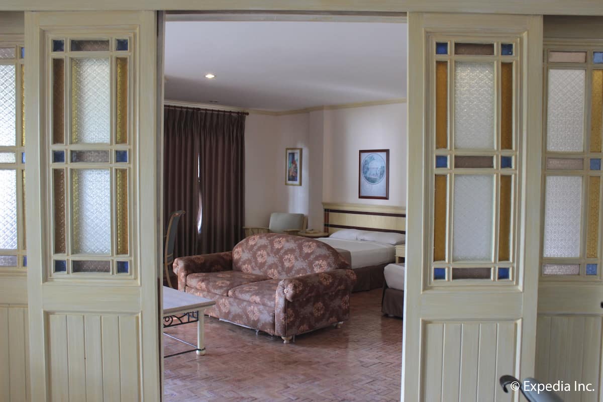 Una habitación de hotel con un sofá estampado, una cama, un escritorio y una silla.
