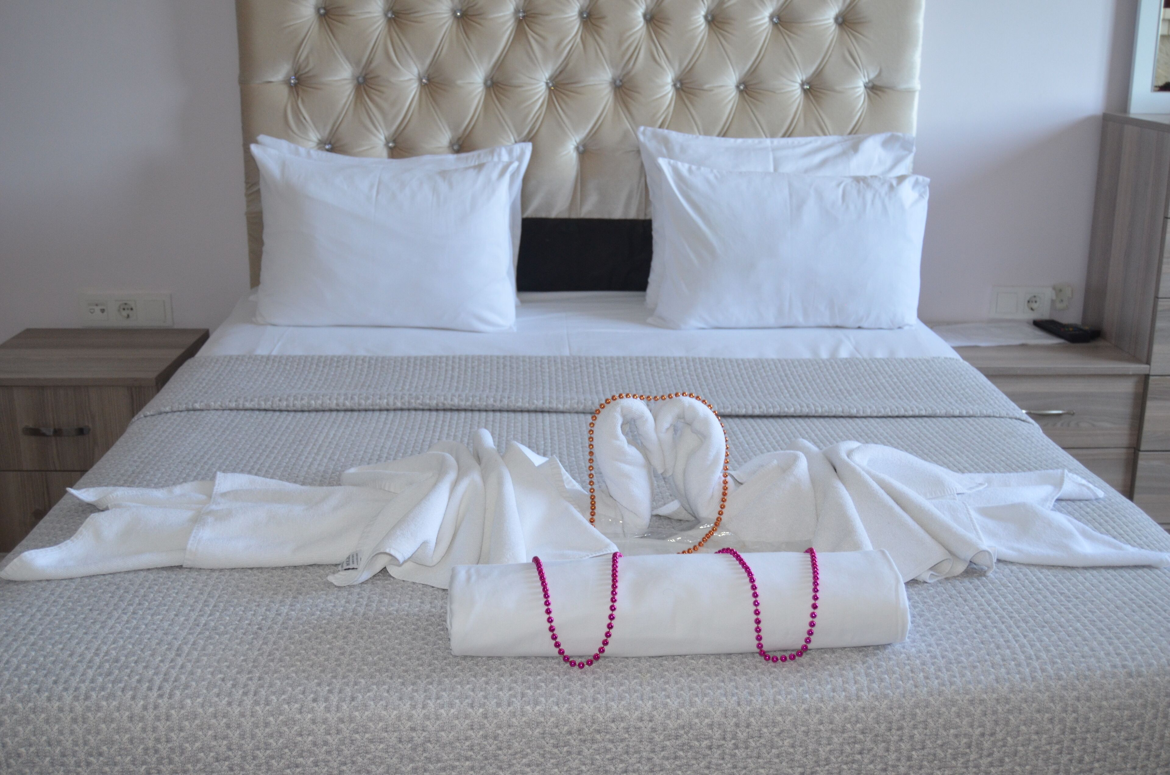 A neatly made bed with white linens and pillows, a bedside table, and a nightstand.