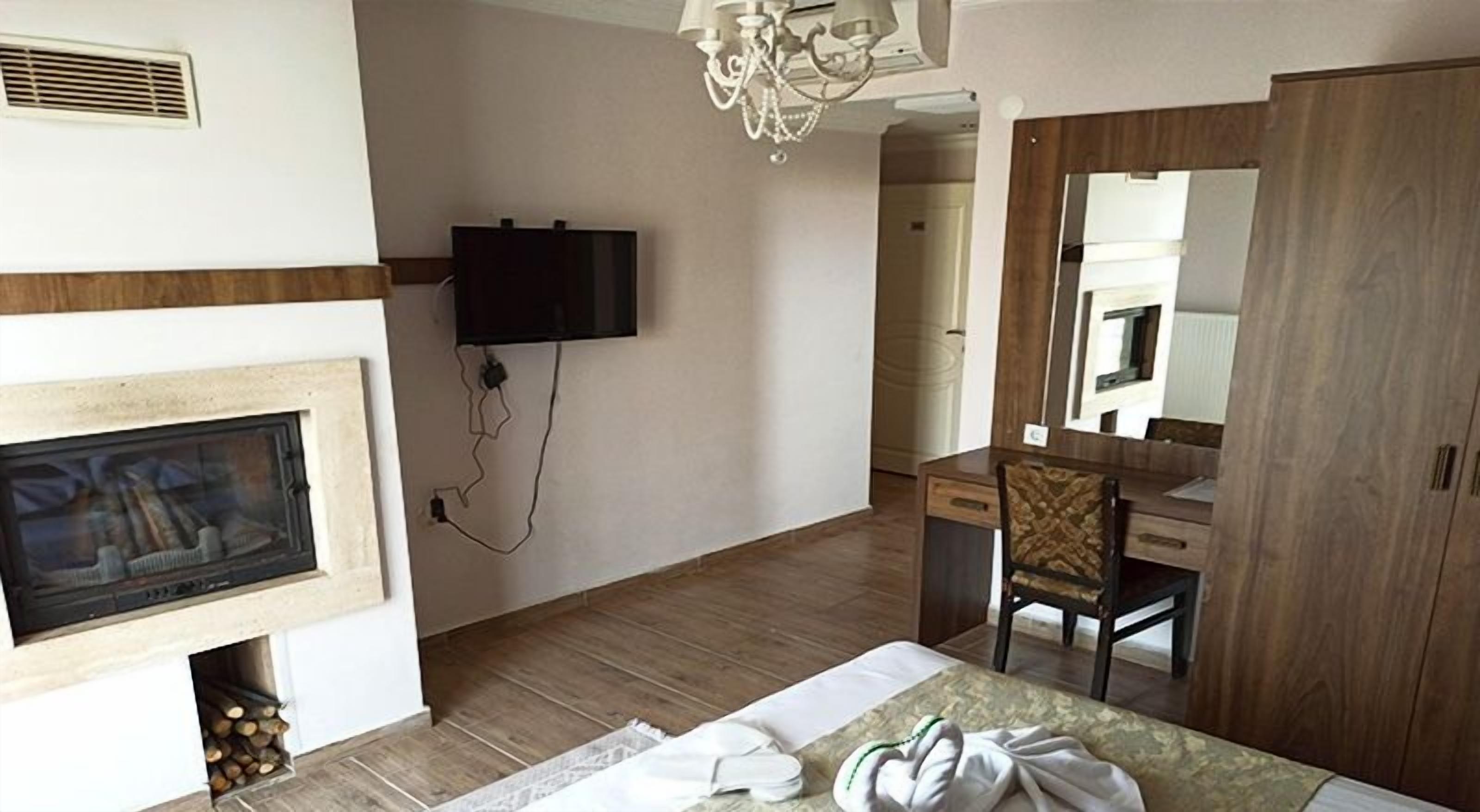 Un dormitorio con chimenea, televisor montado en la pared, armario de madera y espejo.