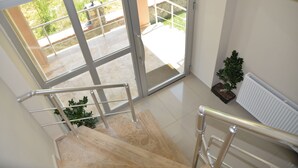 A staircase with metal railings leading to a balcony with a view of greenery outside.