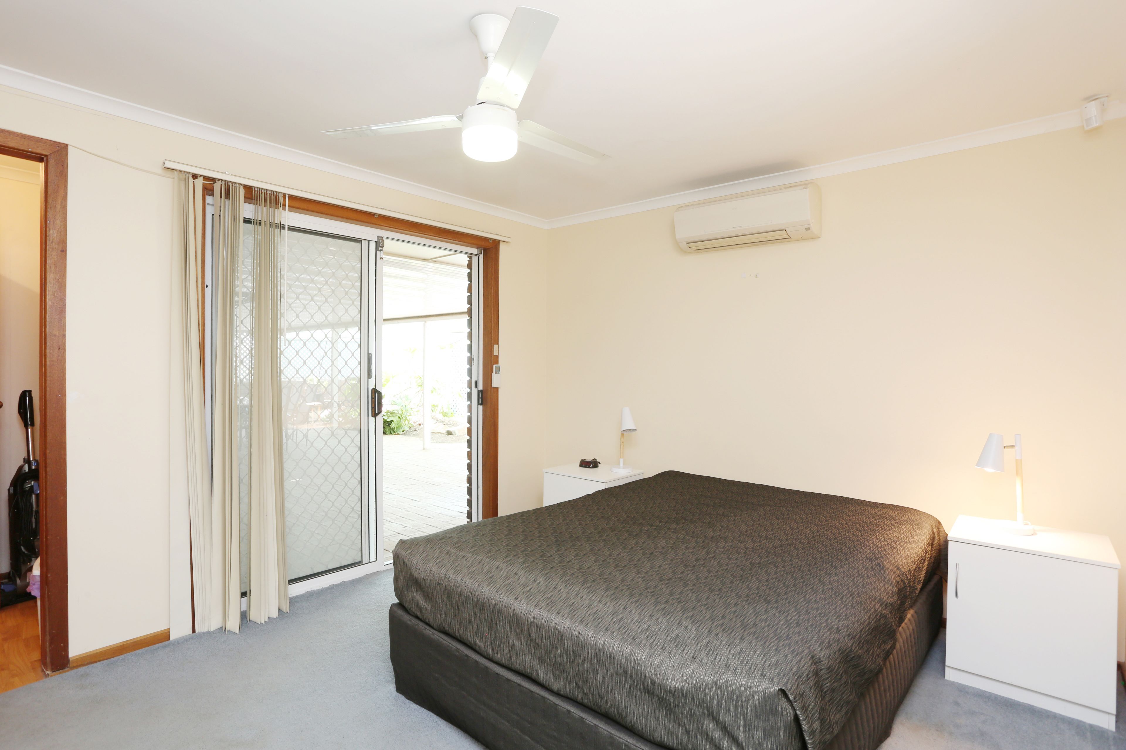 A bedroom with a bed, a nightstand, a ceiling fan, and a sliding glass door leading to an outdoor area.