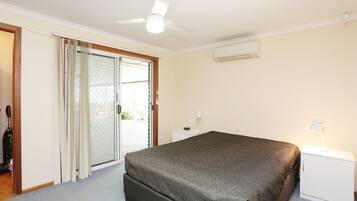 A bedroom with a bed, a nightstand, a ceiling fan, and a sliding glass door leading to an outdoor area.