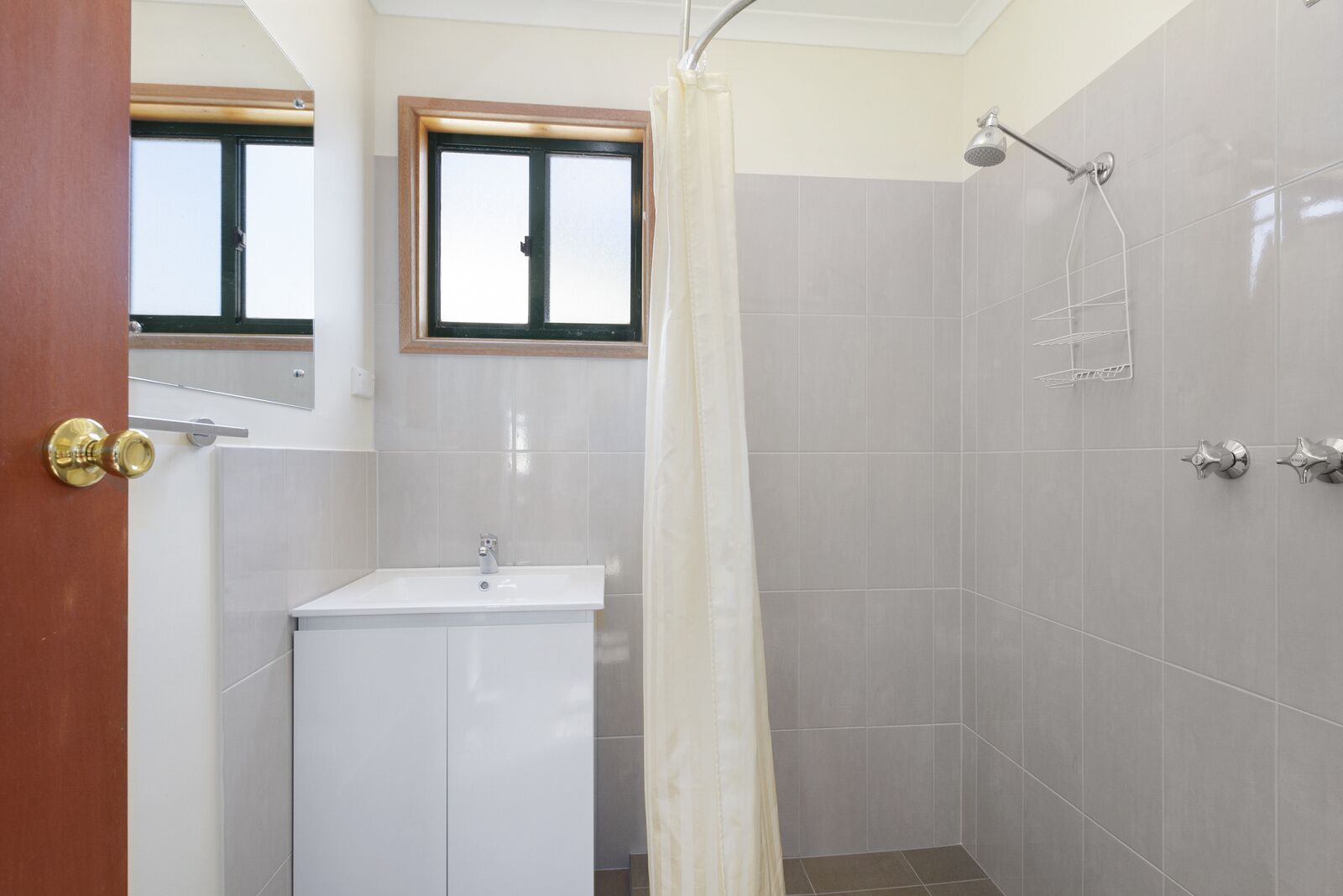 Un baño con ducha, lavabo y ventana.
